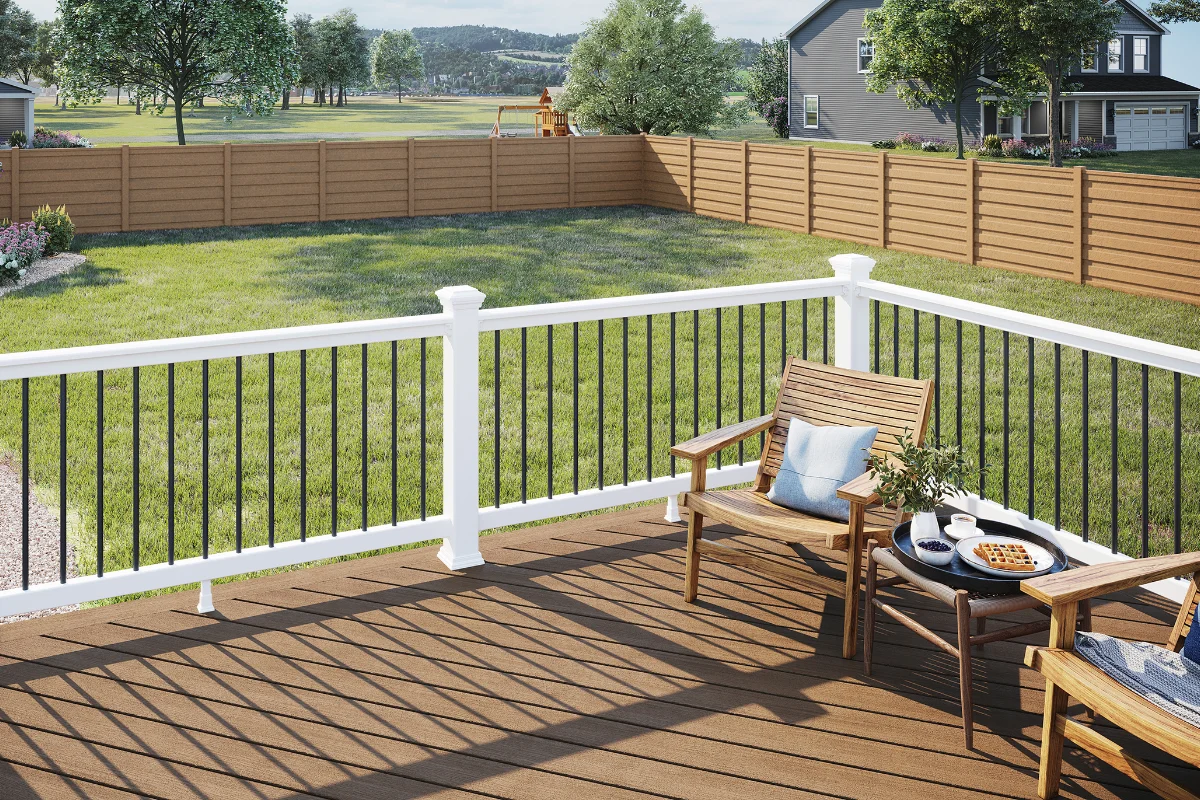 Trex-railing-img-2 Wood deck with white railing and black balusters, two wooden chairs and a small table with waffles and coffee, overlooking a green yard and neighboring houses.